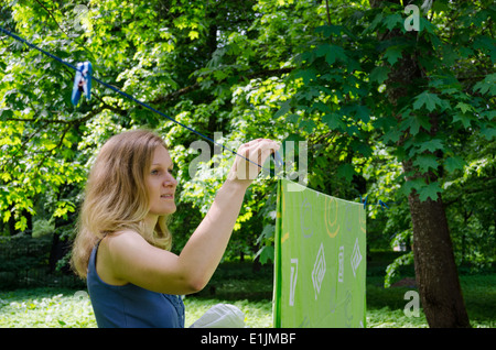 Femme étendre le linge sur la corde à cordes. Ménage en plein air. Banque D'Images