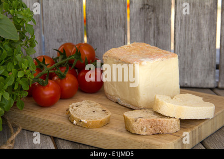 Basilic grec, tomates cerises, fromage taleggio et de pain sur un plateau de fromages Banque D'Images