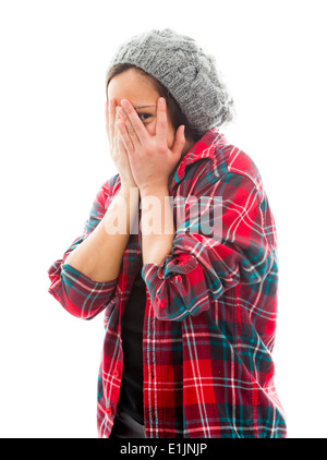 Jeune femme peeking through hands covering face Banque D'Images