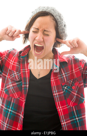 Jeune femme criant avec les doigts dans ses oreilles Banque D'Images