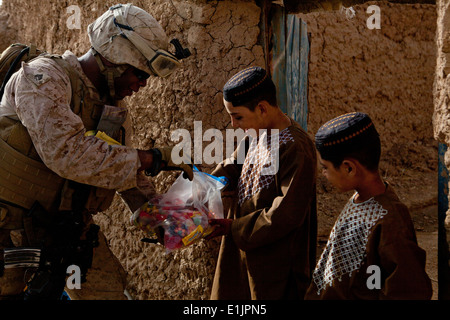 Le sergent du Corps des Marines des États-Unis. Marquel Curtis, gauche, le principal conseiller de liaison avec l'équipe géorgienne (GLT), donne des bonbons à 9 enfants afghans Banque D'Images