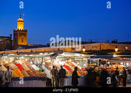 Foule, distributeur des stalles et minaret au crépuscule, la place Jemaa El Fna, Marrakech, Maroc Banque D'Images