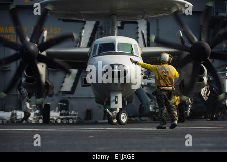 Maître de Manœuvre de la marine américaine (manutention) 3e classe Adrian Ramilo dirige les pilotes d'un E-2C Hawkeye aéronefs affectés à Airbor Banque D'Images