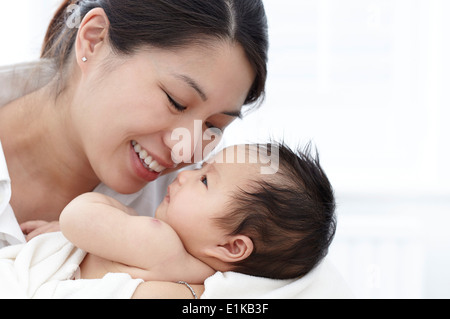 Parution modèle Mother smiling and holding baby girl. Banque D'Images