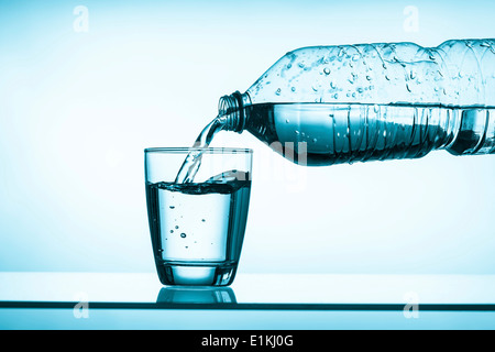 L'eau minérale est versé dans le verre de boisson. Banque D'Images