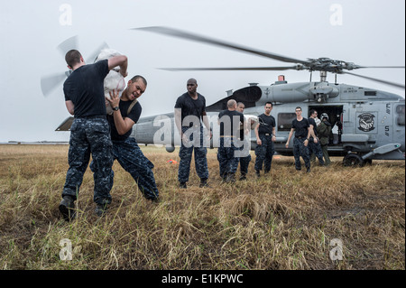 Les marins américains affectés au porte-avions USS George Washington (CVN 73) charger des fournitures de secours sur une Marine MH-60R Seahawk il Banque D'Images