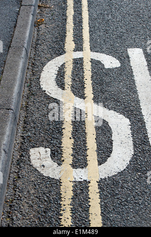 Marquage routier signe lent peint avec double ligne jaune pour ressembler à un symbole du dollar Banque D'Images