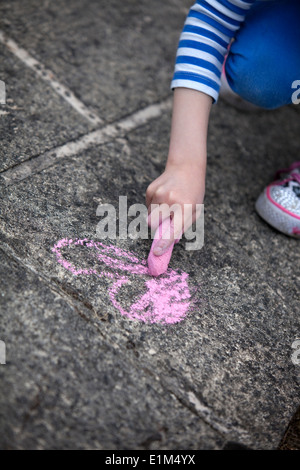 Dessin de l'enfant une craie rose coeur sur un trottoir en béton. Banque D'Images