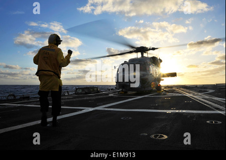 La Marine américaine maître de Manœuvre 2e classe Robert Titus donne des signes de la main à un SH-60B Seahawk hélicoptère sur le pont d'envol du Banque D'Images