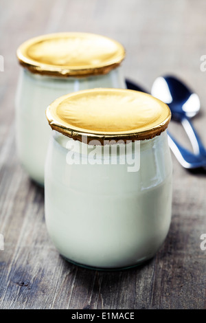 La crème sure ou yogourt nature avec des cuillères - santé et alimentation concept Banque D'Images