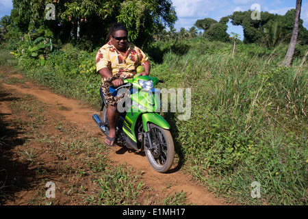 L'île de Rarotonga. L'île de Cook. Polynésie française. Océan Pacifique Sud. Deux personnes obèses conduire une motocyclette sur une route sur l'île Banque D'Images