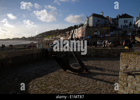Le quai pavé et le port historique de Lyme Regis, avec une grande sculpture d'ancre au premier plan, Dorset, Royaume-Uni. Banque D'Images