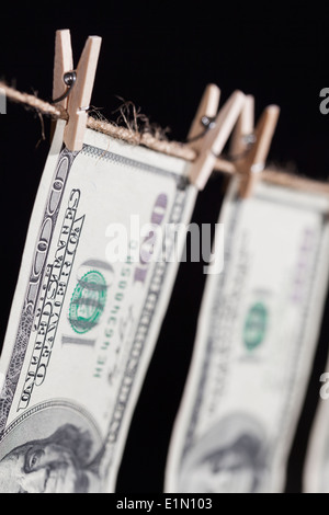 Hundred Dollar Bills suspendu à une corde sur un fond sombre. Banque D'Images