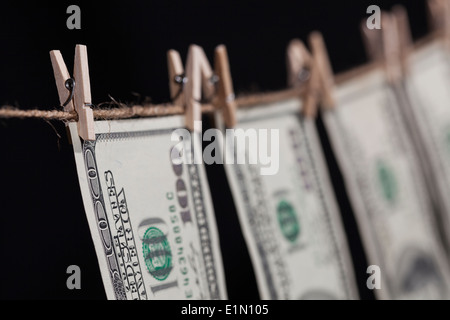 Hundred Dollar Bills suspendu à une corde sur un fond sombre. Banque D'Images