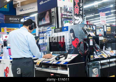 Tokyo Japon 2014 - Homme d'essayer un casque dans un magasin d'électronique Banque D'Images