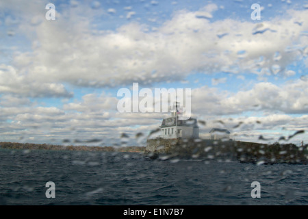 Le phare sur l'île à distance vu à travers la fenêtre de tempête Banque D'Images