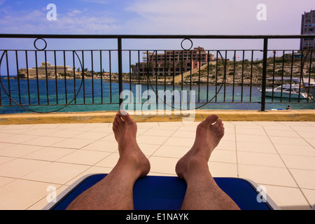 L'homme de vous détendre sur un balcon de l'hôtel solarium. Banque D'Images