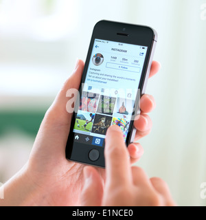 Personne ayant un tout nouveau Apple iPhone 5S avec profil Instagram sur l'écran. Banque D'Images