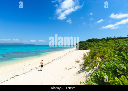 L'homme parfait admiratifs plage de sable blanc entourée d'eau tropicale d'Okinawa, Japon Banque D'Images