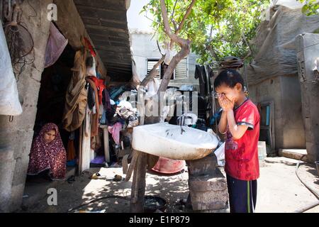 La ville de Gaza, la bande de Gaza. 8 juin, 2014. Un jeune garçon palestinien lave son visage à l'extérieur de la tente de sa famille, où ils vivent depuis deux ans après que le gouvernement a évacué de l'ancienne police. La lutte de la famille tout en vivant sous le seuil de pauvreté à Al Zaitoun alentours dans la ville de Gaza. © Eman Mohammed/ZUMAPRESS.com/Alamy Live News Banque D'Images