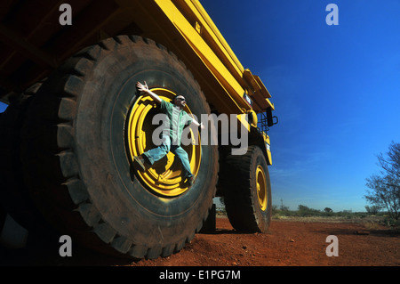 Man climbing sur énorme roue de camion minier haulpak, Newman, région du Pilbara, Australie occidentale. Pas de monsieur Banque D'Images