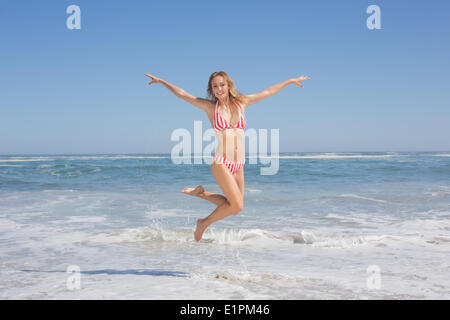 Happy fit woman in bikini jumping on the beach Banque D'Images