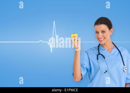 Libre de surgeon holding an apple and smiling at camera Banque D'Images