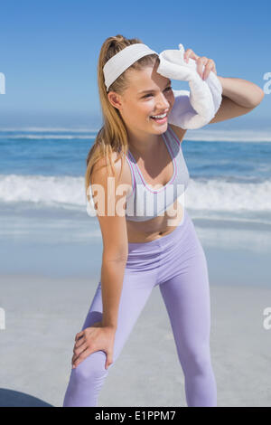 Blonde sportive debout sur la plage avec une serviette Banque D'Images