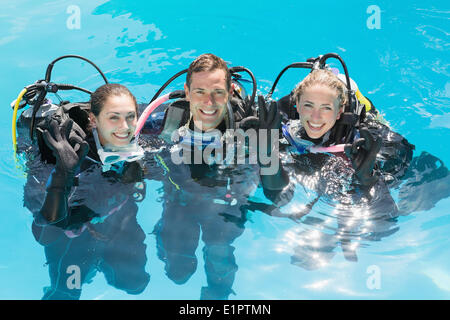 Smiling friends sur scuba training in swimming pool looking at camera Banque D'Images