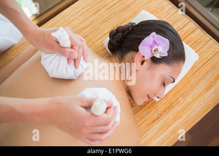 Smiling woman getting a massage dos avec compresse aux herbes Banque D'Images