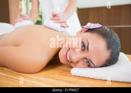 Smiling woman getting a massage dos avec compresse aux herbes Banque D'Images