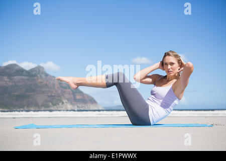 L'accent fit blonde faisant du yoga sur la plage Banque D'Images