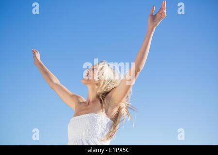 Femme en robe blanche debout avec les bras tendus Banque D'Images