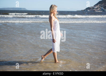 Femme en robe blanche marche dans la mer Banque D'Images