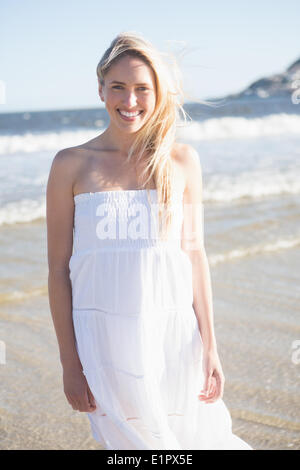 Femme en robe blanche smiling at camera sur la plage Banque D'Images
