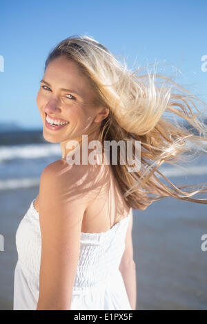 Femme en robe blanche smiling at camera sur la plage Banque D'Images