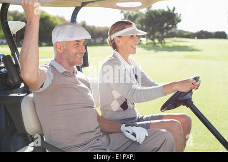 Golf heureux couple smiling in leur Buggy Banque D'Images