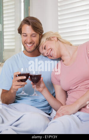 Heureux couple sitting on couch with red wine Banque D'Images
