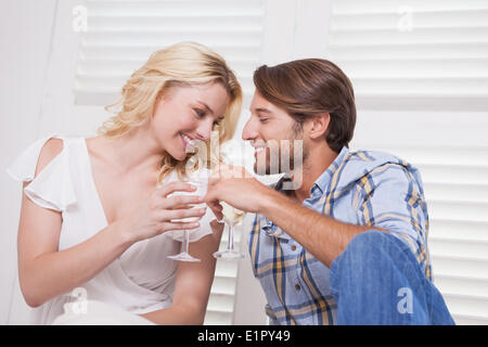 Young couple sitting on floor drinking wine Banque D'Images