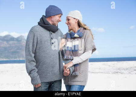 Smiling couple debout sur la plage, dans des vêtements chauds Banque D'Images