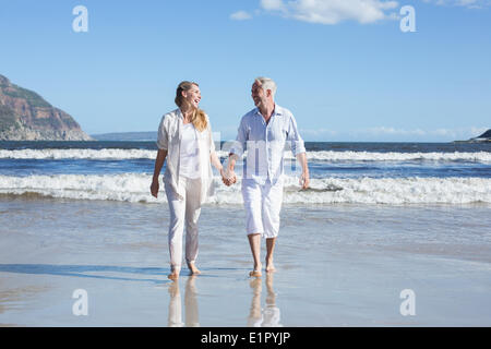 Heureux couple marche pieds nus sur la plage Banque D'Images