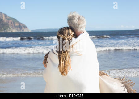 Couple jusqu'en couverture sur la plage face à la mer Banque D'Images