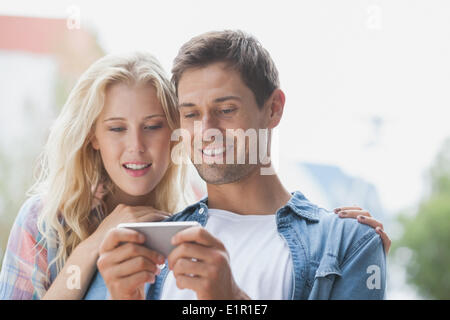 Cute young couple looking at smartphone Banque D'Images