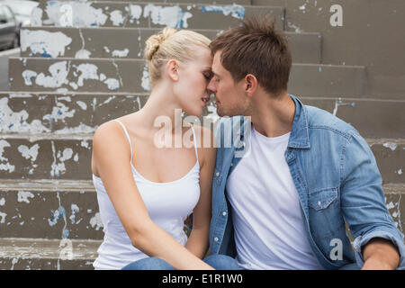 Hip young couple sitting on steps kissing Banque D'Images