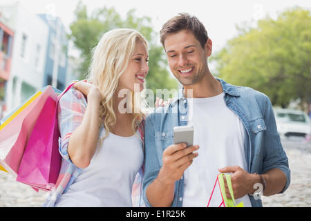 Hip young couple looking at smartphone sur shopping trip Banque D'Images