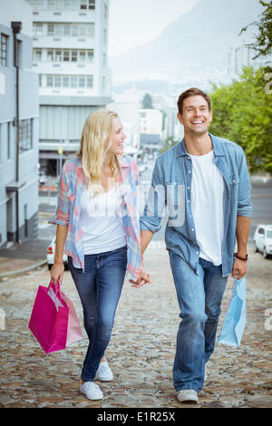 Jeune couple sur la hanche sortie shopping marche en montée Banque D'Images