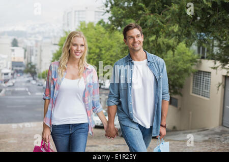 Jeune couple sur la hanche sortie shopping marche en montée Banque D'Images