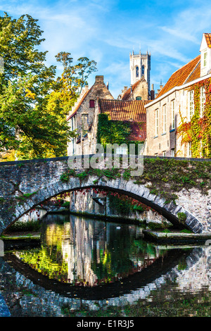 Canal et pont de pierre à Bruges, Belgique le long Steenhouwersdijk avec la tour du beffroi derrière. Banque D'Images