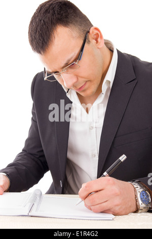 De graves portant des lunettes écrit avec un stylo dans le bloc-notes Banque D'Images