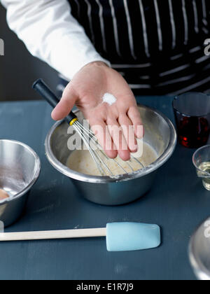 En ajoutant une pincée de sel pour la pâte à crêpes Banque D'Images